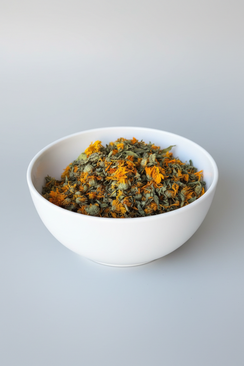 White bowl filled with dried marigold flowers on a light background